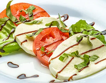 Sliced tomatoes, mozzarella, and basil served as a Caprese salad at Anthony’s Coal Fired Pizza light and fresh Italian food.