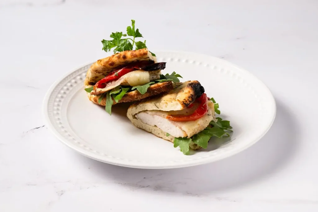 Roasted chicken sandwich with lettuce and tomato on fresh bread at Anthony’s, coal fired flavor in every Italian-style bite.