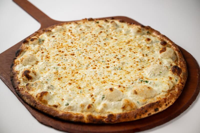 Coal fired white pizza with a golden, bubbling cheese blend, garlic, and fresh parsley over a crisp charred crust, rich in creamy flavor and texture.