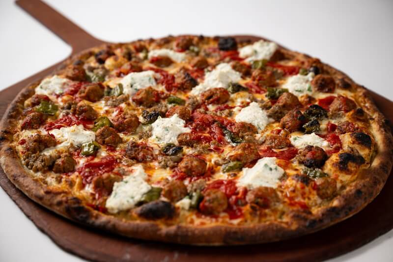 Coal fired pizza topped with meatballs, Italian sausage, sweet peppers, and creamy ricotta, served on a crisp charred crust with bold, hearty flavor.