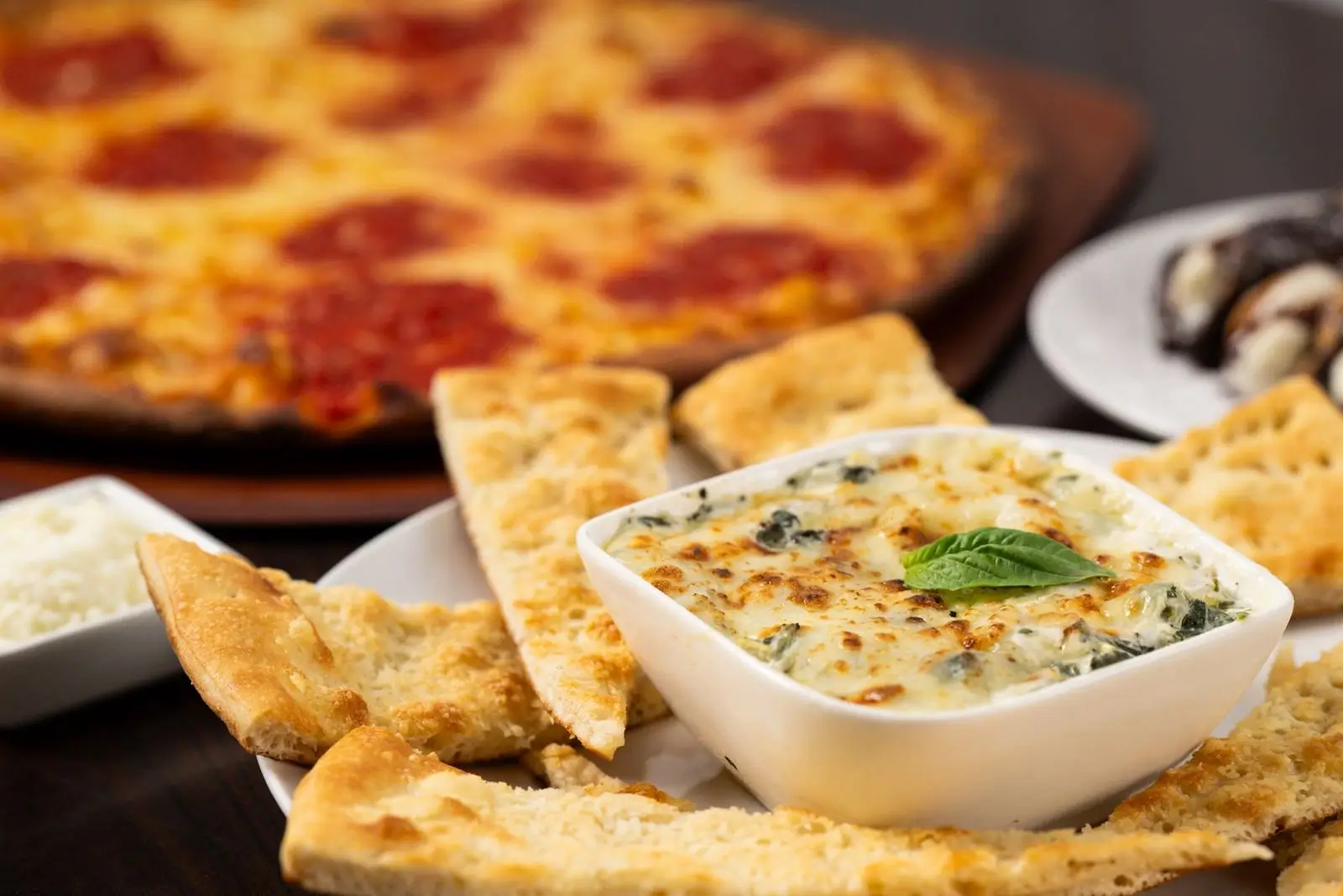 Creamy spinach and artichoke dip with cheeses and bold Italian flavor, served warm at Anthony’s Coal Fired Pizza before your meal.